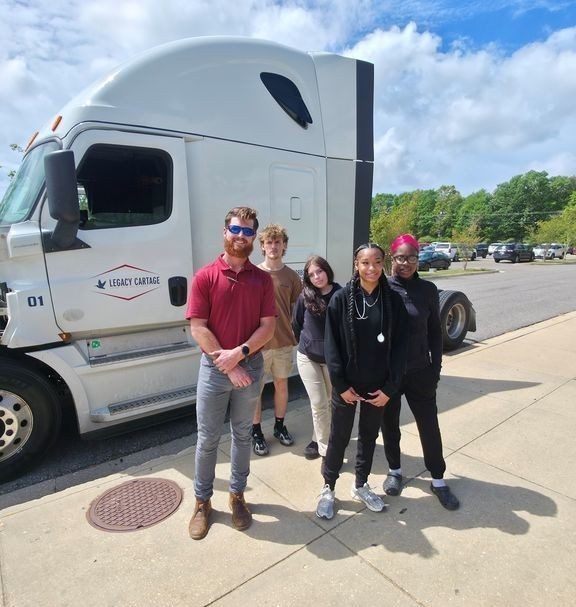 A man and four Theodore High students standing by a semi truck