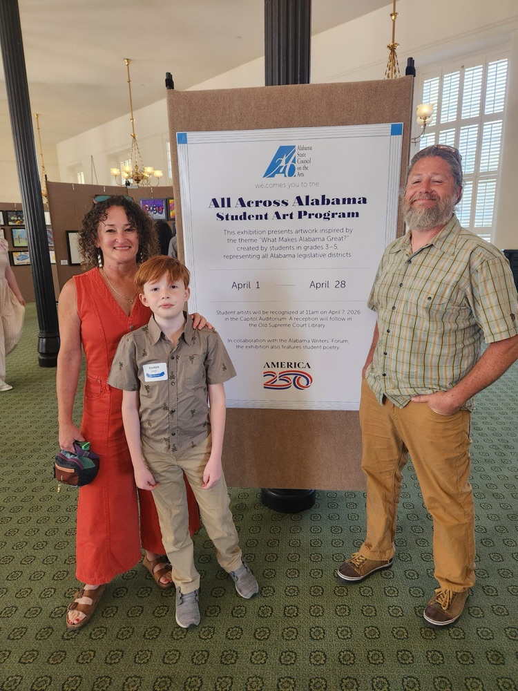 Ruston and his mom and dad standing in front of the all across Alabama student art program poster