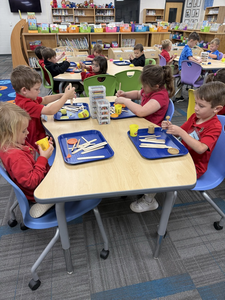 pre-K students building with Play-Doh and craft sticks in the library
