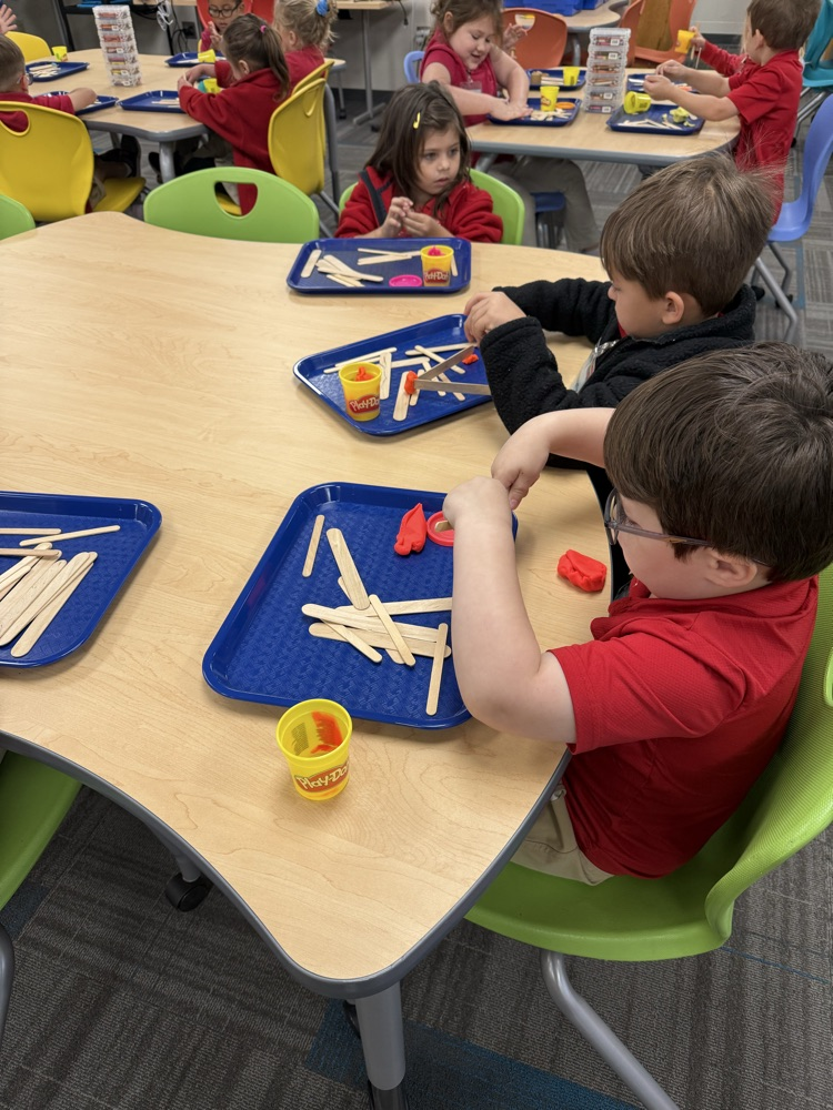 pre-K students building with Play-Doh and craft sticks in the library