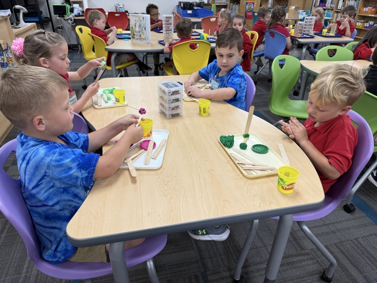pre-K students building with Play-Doh and craft sticks in the library