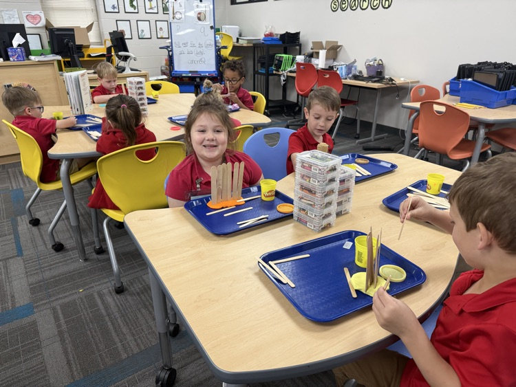 pre-K students building with Play-Doh and craft sticks in the library