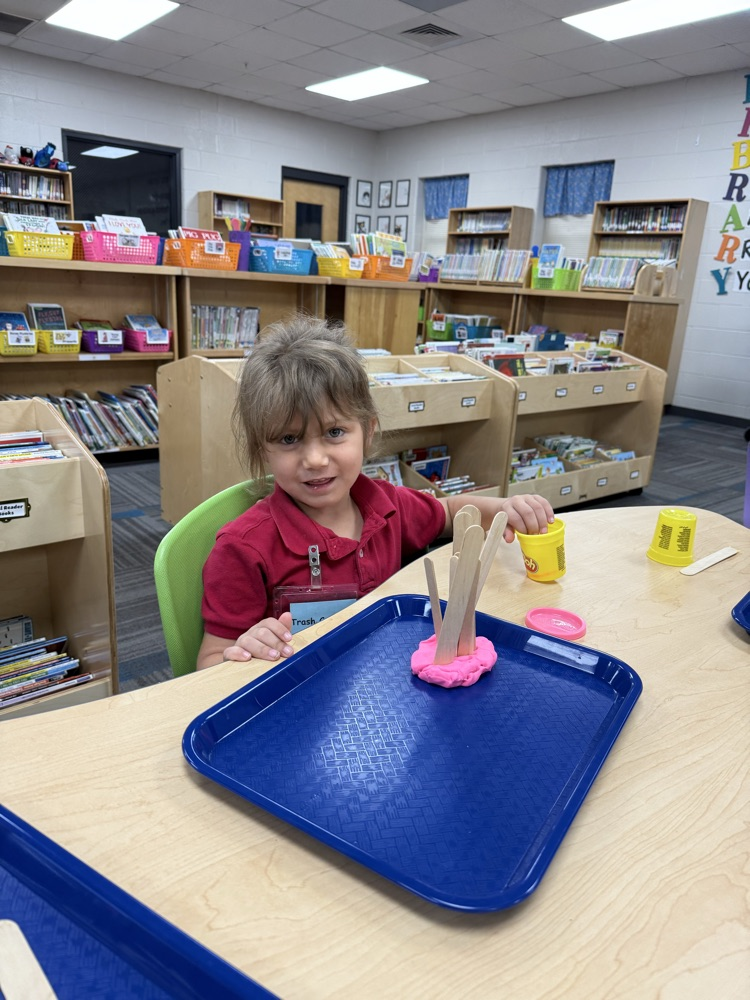 pre-K students building with Play-Doh and craft sticks in the library