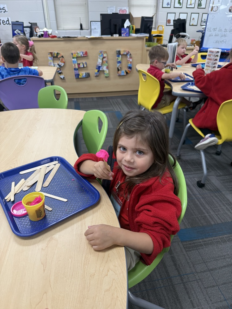 pre-K students building with Play-Doh and craft sticks in the library
