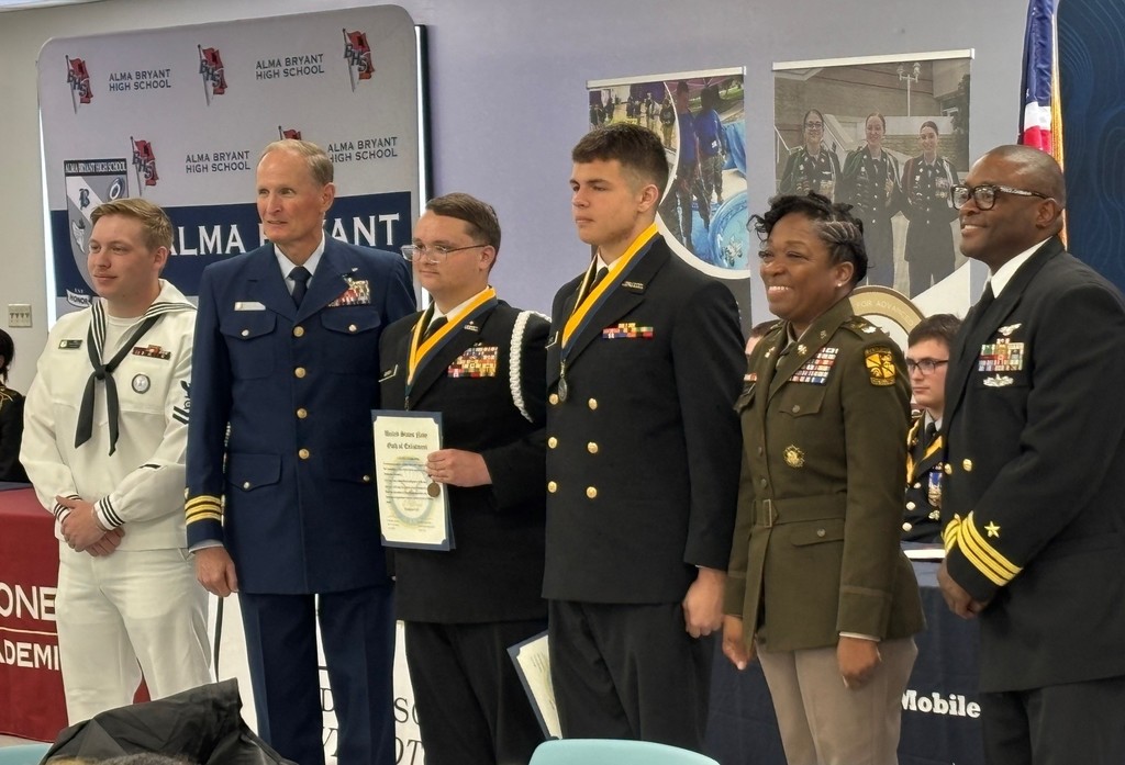Military officers and JROTC instructors stand with two cadets