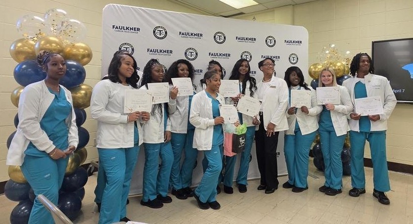 A group of Faulkner students in scrubs, holding certificates