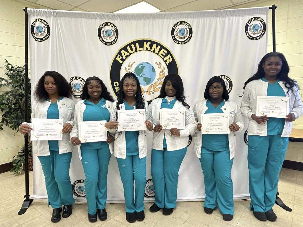 A group of Faulkner students in scrubs, holding certificates