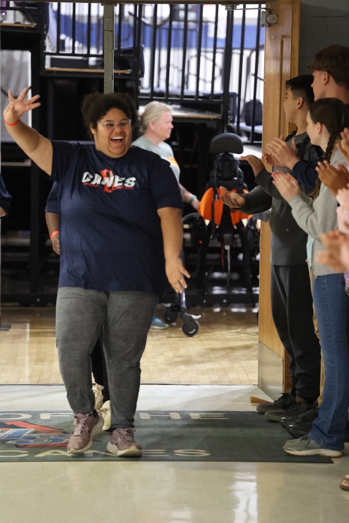 An Alma Bryant student smiles and waves as others clap for her