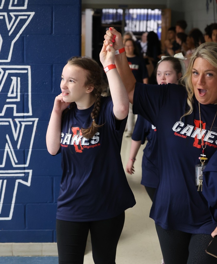 A teacher holds an Alma Bryant student's arm in the air as they walk down a hall