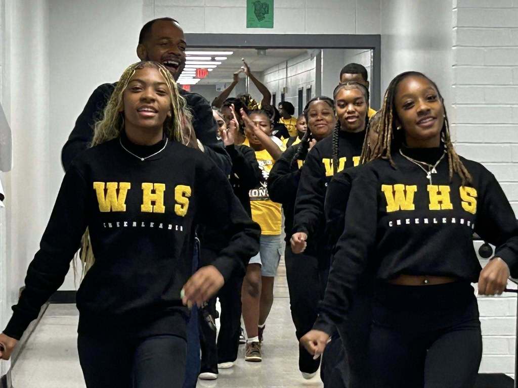 Williamson cheerleaders lead a parade of students down a hallway