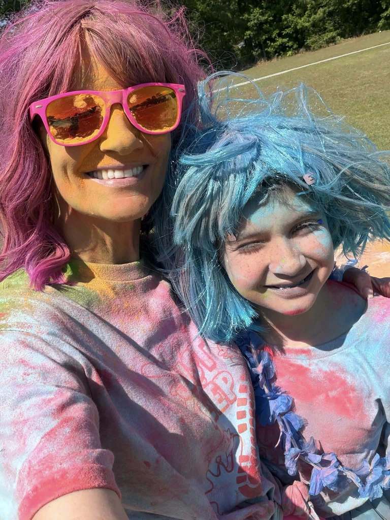 A teacher and a student in colorful wigs, with chalk on their faces
