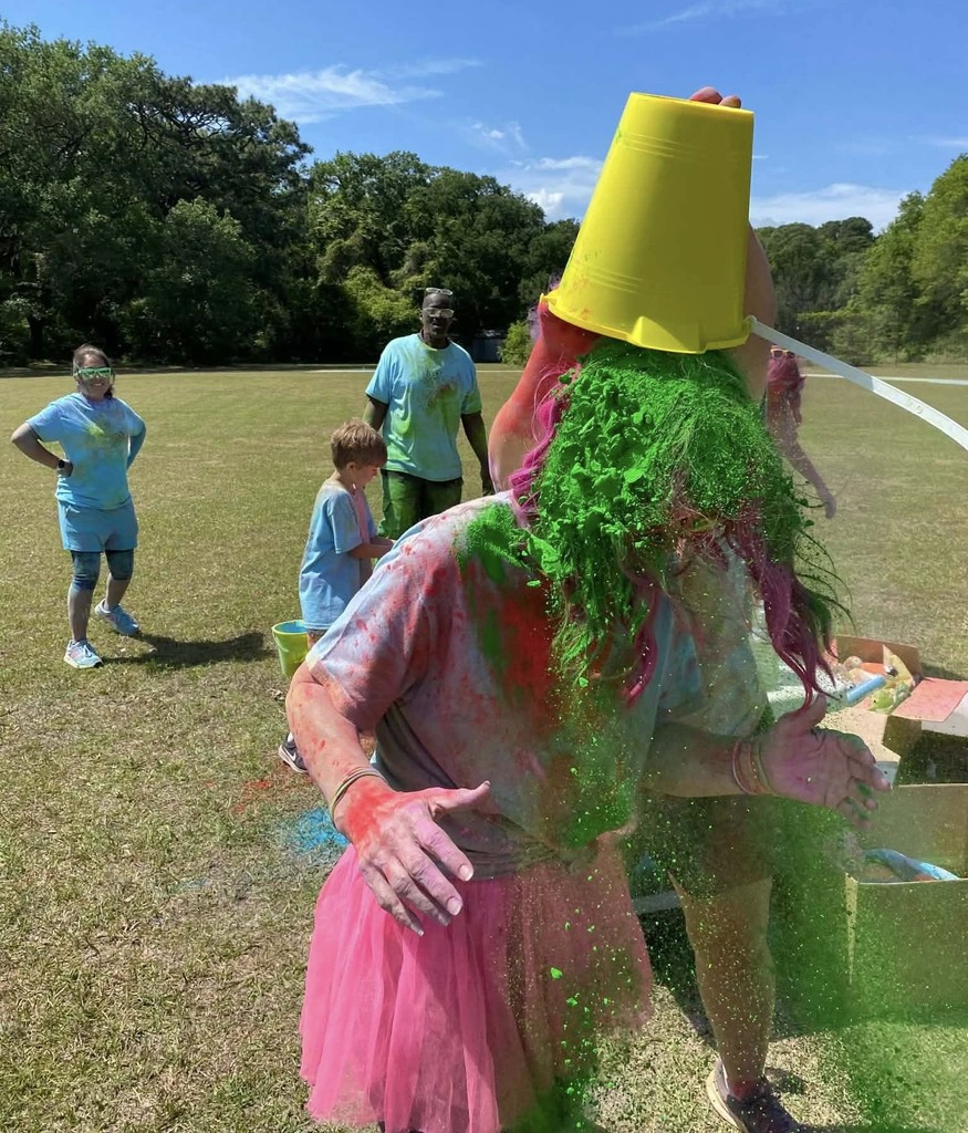 A teacher dumps a bucket of green chalk onto another teacher's head