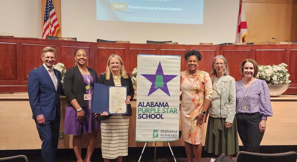 Taylor-White Principal Sonia Andrews holds a certificate while standing with State Education Superintendent Dr. Eric Mackey and several board members