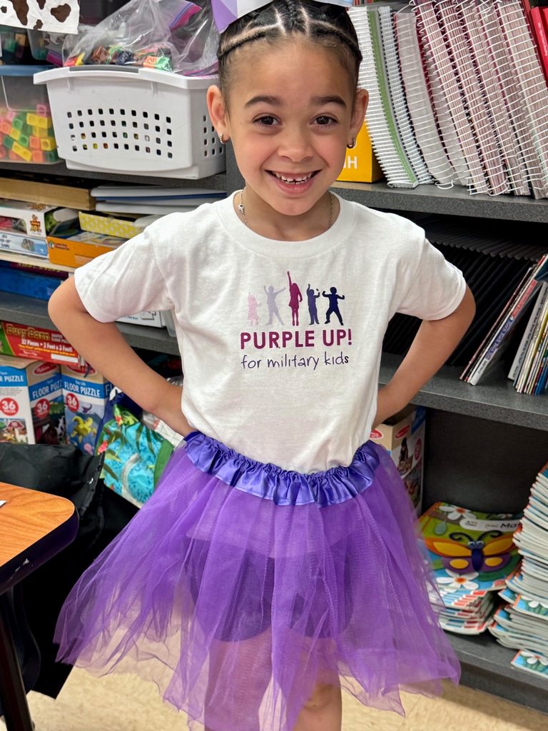 A girl wearing a tutu and a shirt that reads "Purple Up for military kids"