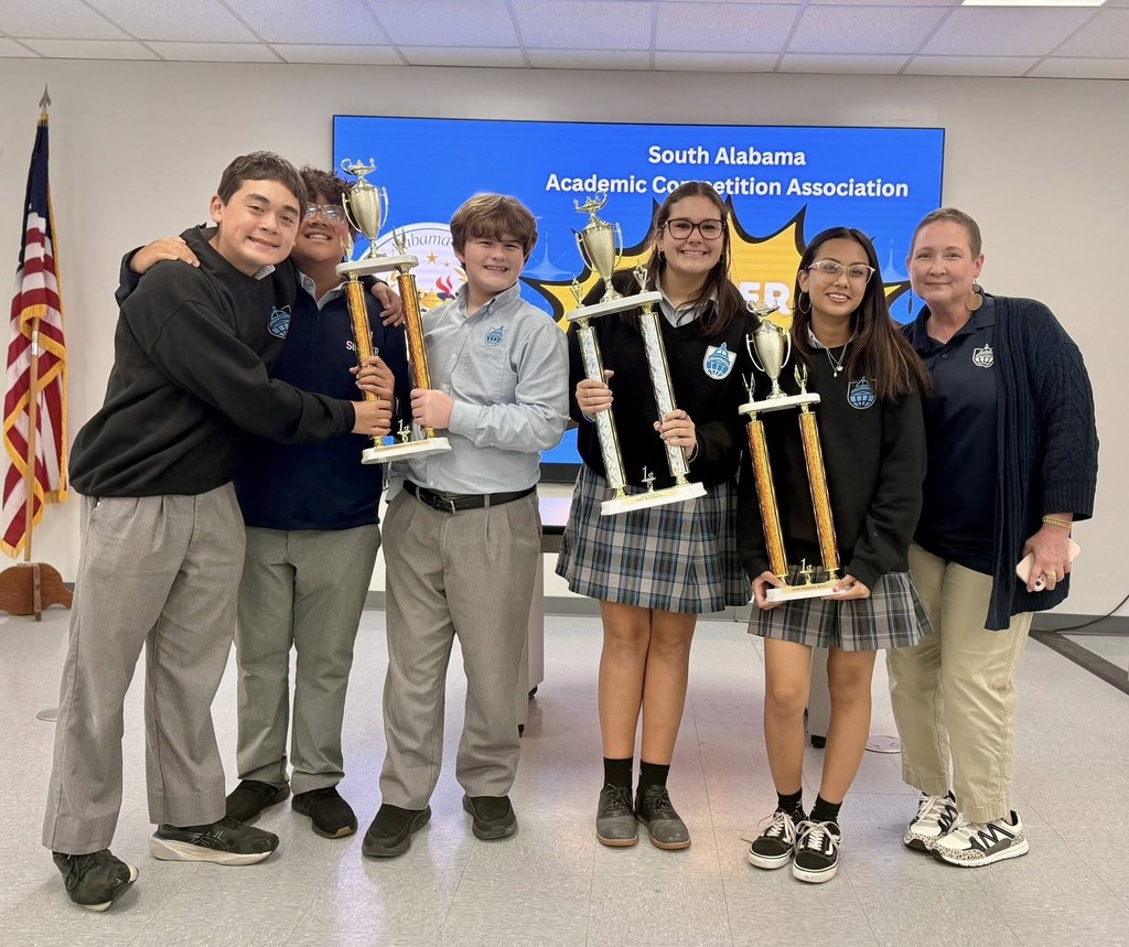 Barton Academy students holding three trophies