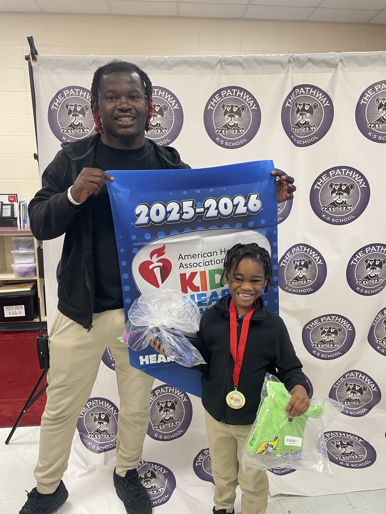 Students standing with the PE coach. The coach is holding a banner that read "American heart Association Kids Heart Challenge". The  students are holding up rewards they've earned for completing the challenge 