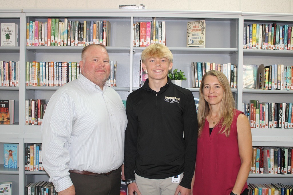 Davidson student Owen Farmer stands with his parents in the school library