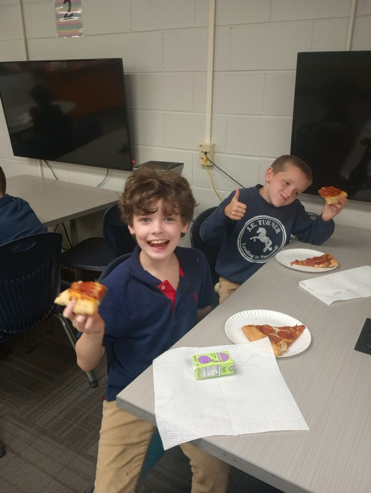 two students holding up pizza 