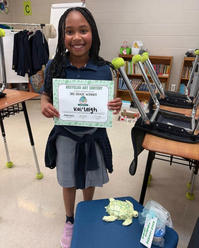 A girl with a certificate and a toy turtle made of recycled paper
