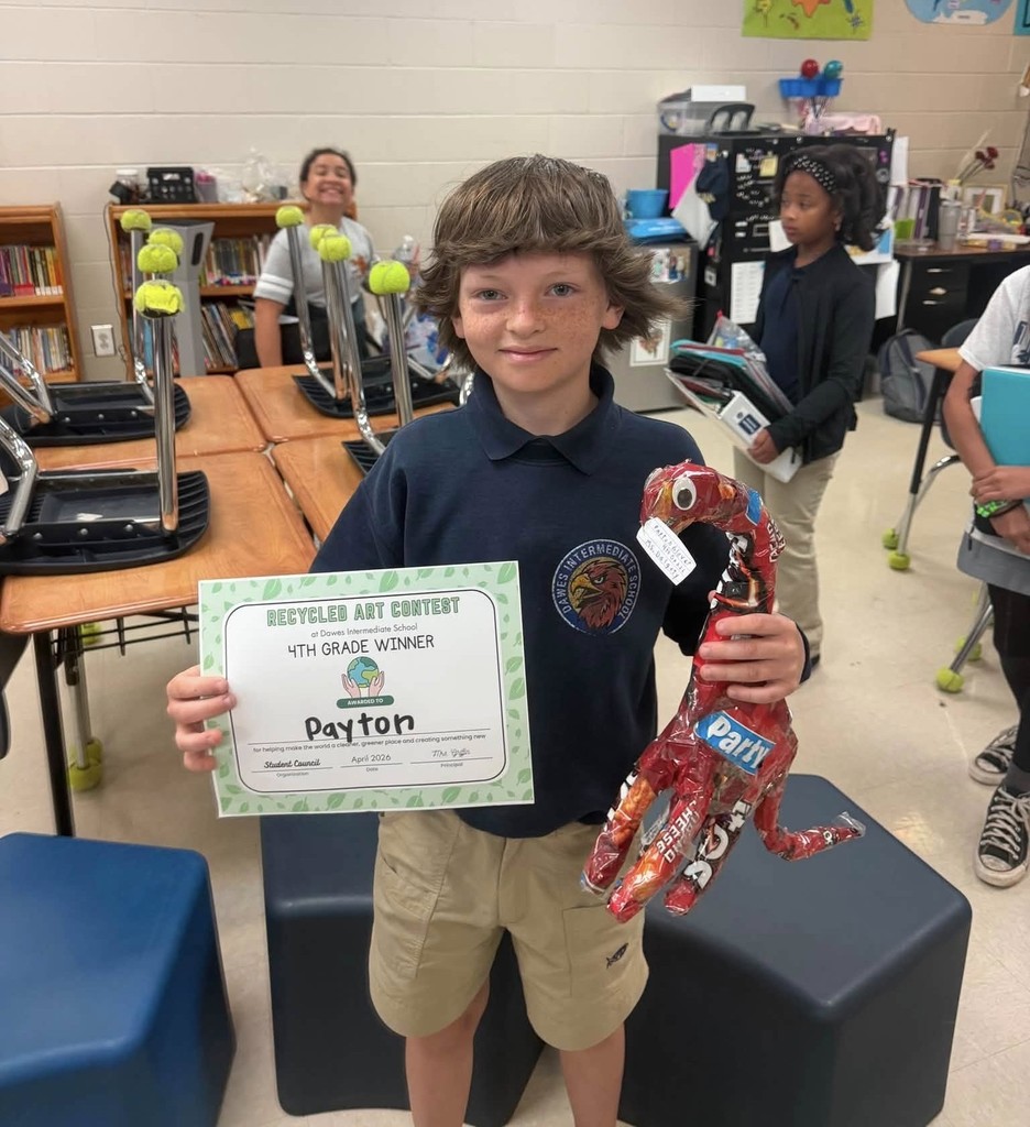 A boy holding a certificate and a toy dinosaur made of potato chip bags