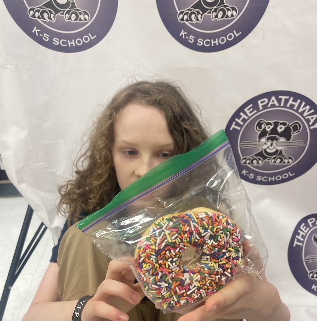 Student holding a doughnut with rainbow sprinkles 