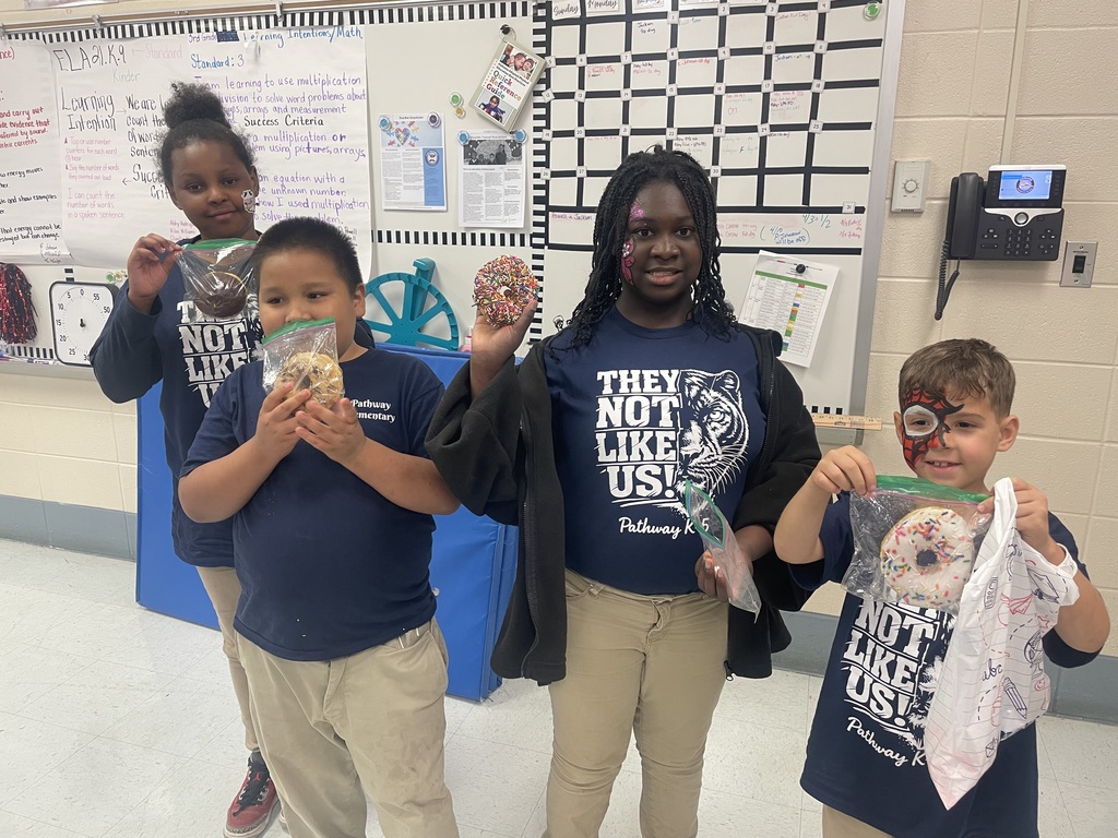 Students holding up doughnuts 