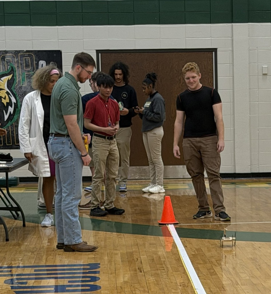 Students watching a mousetrap car in a gymnasium