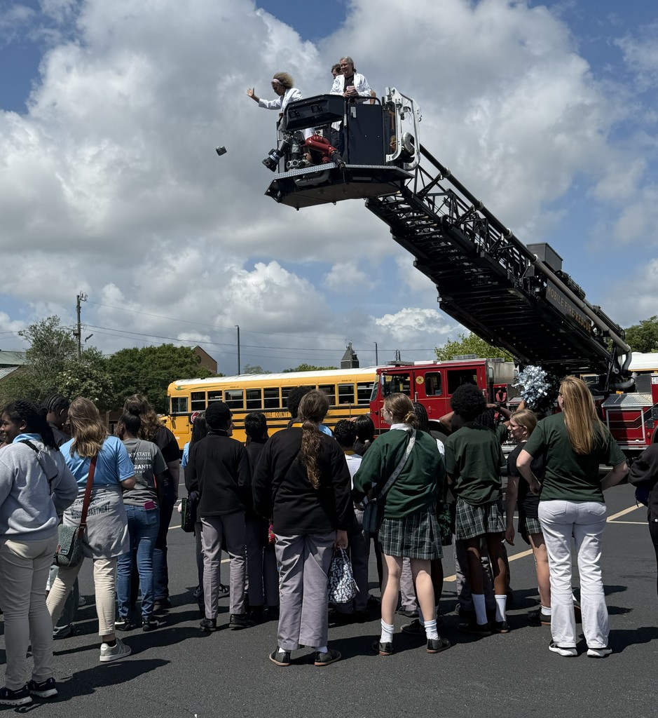 Students watch as teachers drop an egg from the raised ladder of a fire truck