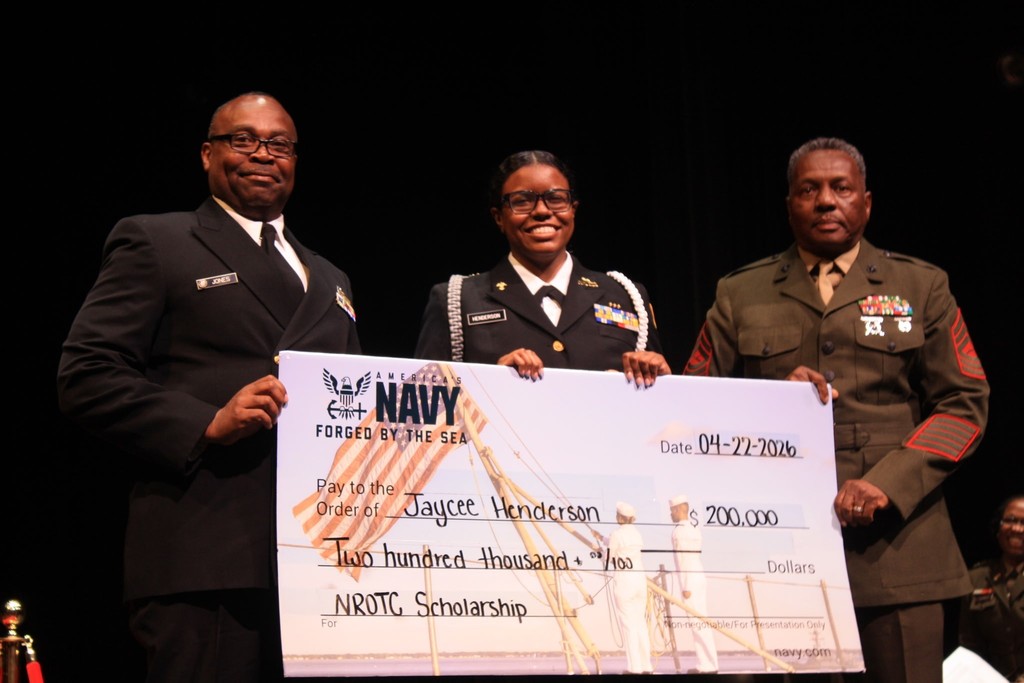 Jaycee Henderson and two men in uniform holding an oversized check for $200,000