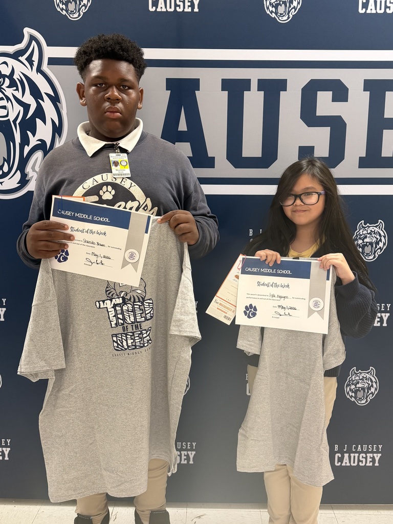 2 students holding up t-shirts and certificates