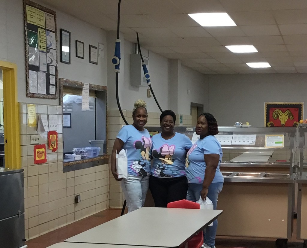 Two cafeteria staff members and the cafeteria manager stands next to each other with their gift bag in their hand.