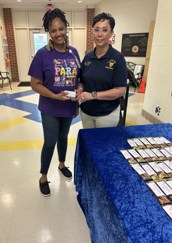 Mrs. Kidd with a para passing out the Hershey bar for day 3 of teacher appreciation 
