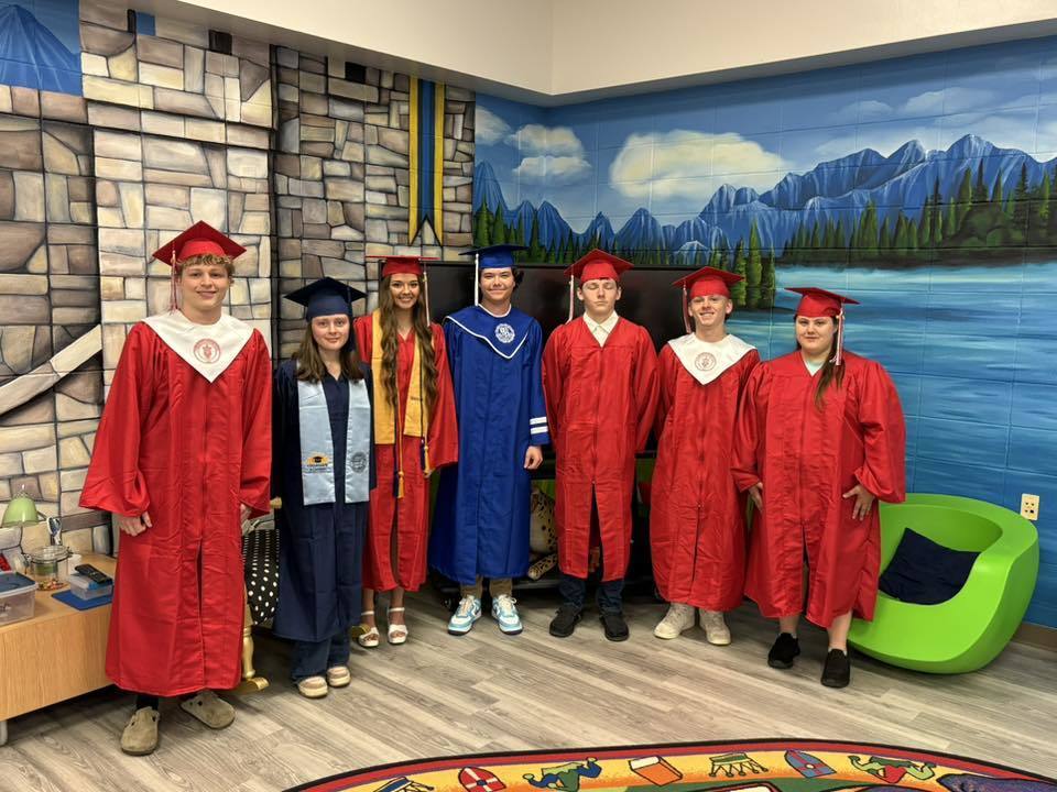 A group of seniors in caps and gowns standing in school library