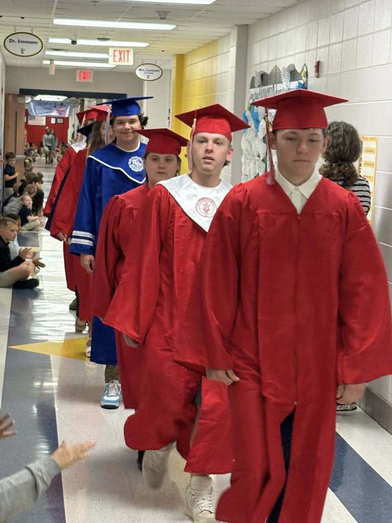 Seniors in caps and gowns walking down a hallway