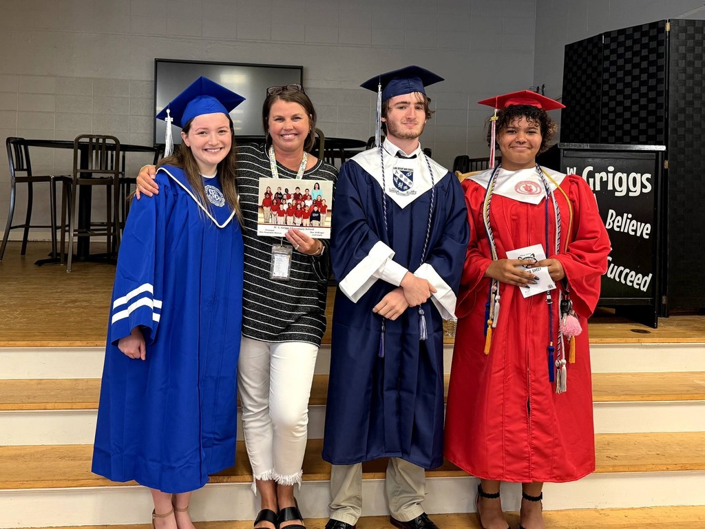 Three seniors in caps and gowns stand with a teacher at Griggs Elementary