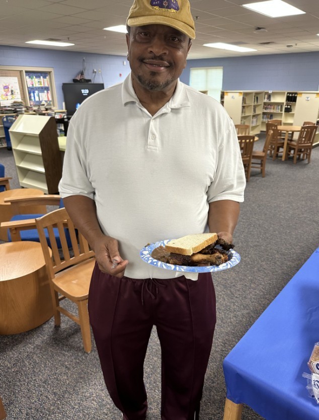 Coach Turner holding his plate of food with a big smile 
