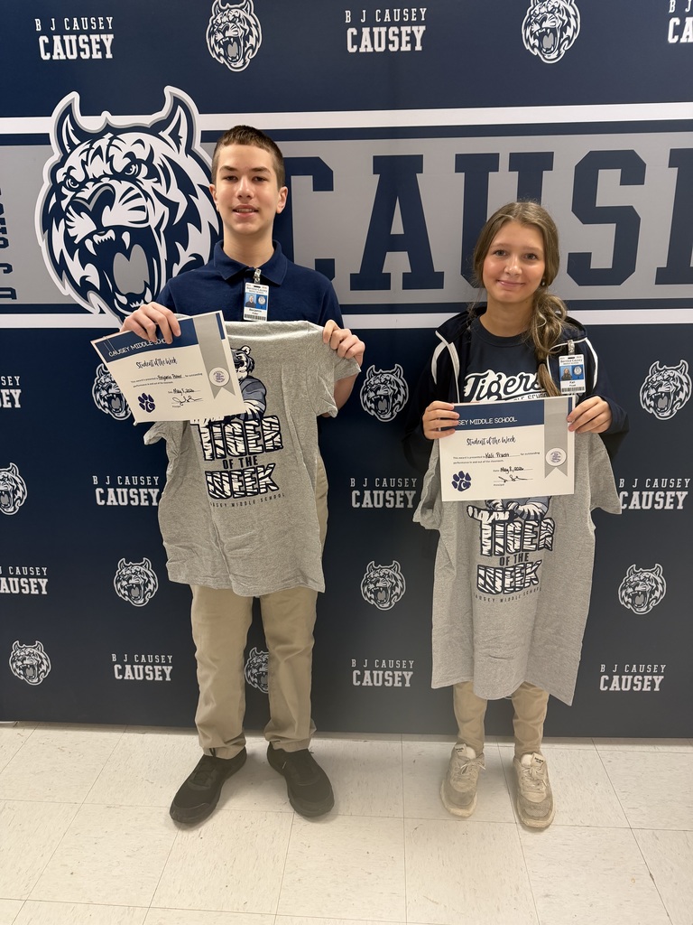 2 students holding up t-shirts and certificates