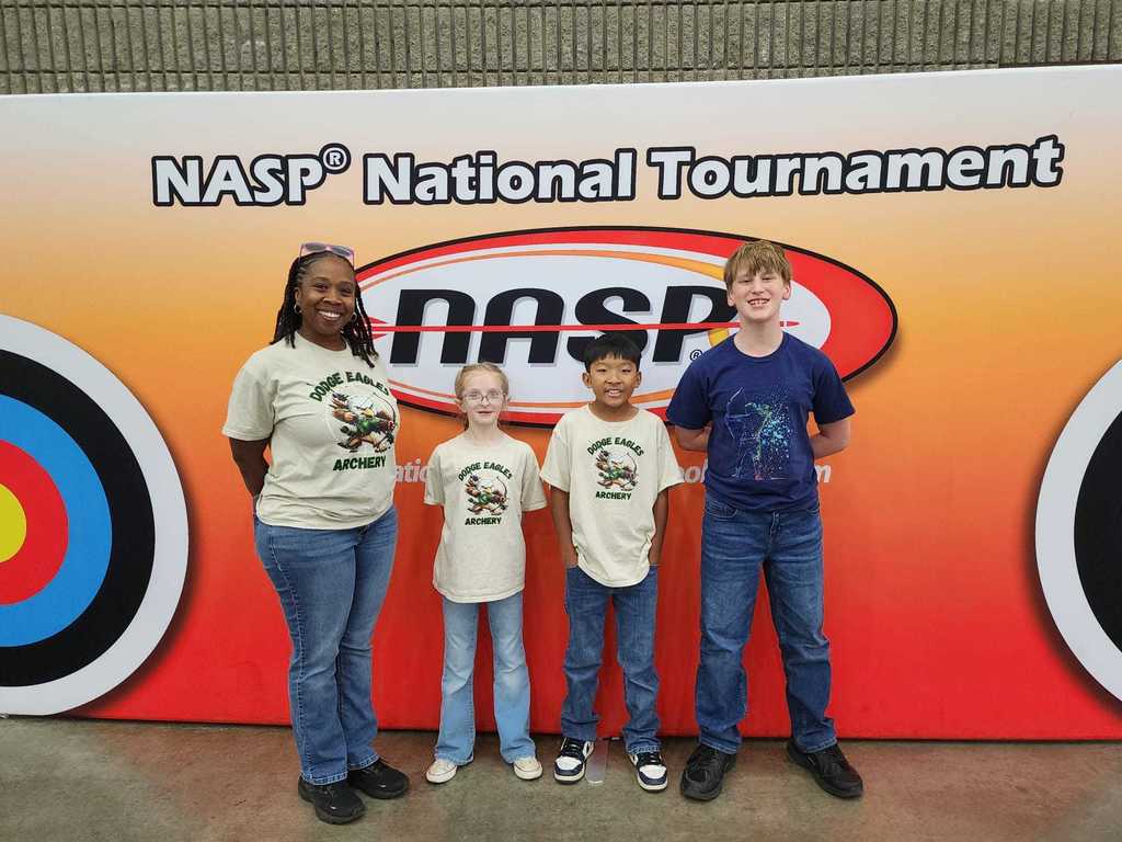 three children and a woman stand in front of a NASP National Tournament backdrop with targets.