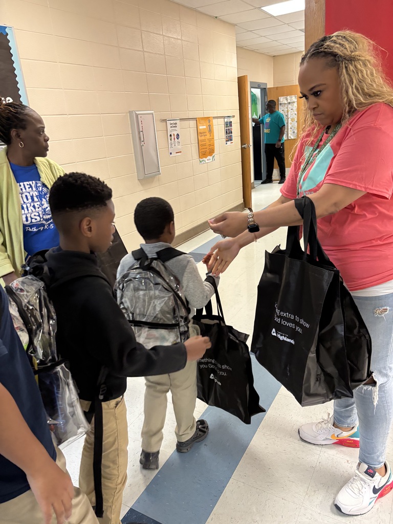Students lined up in the hallway to receive their bag. Teachers are helping pass out bags to ensure each child receives one 