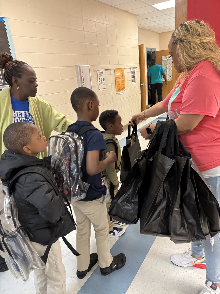 Students lined up in the hallway to receive their bag. Teachers are helping pass out bags to ensure each child receives one 