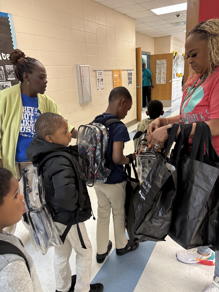 Students lined up in the hallway to receive their bag. Teachers are helping pass out bags to ensure each child receives one 