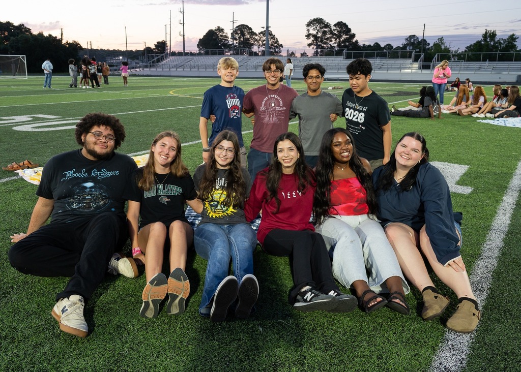 A group of Davidson students sitting on the turf at the football field