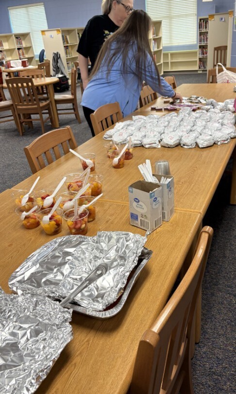 Breakfast food items on the table (fruit cups and Chick Fil A biscuits)