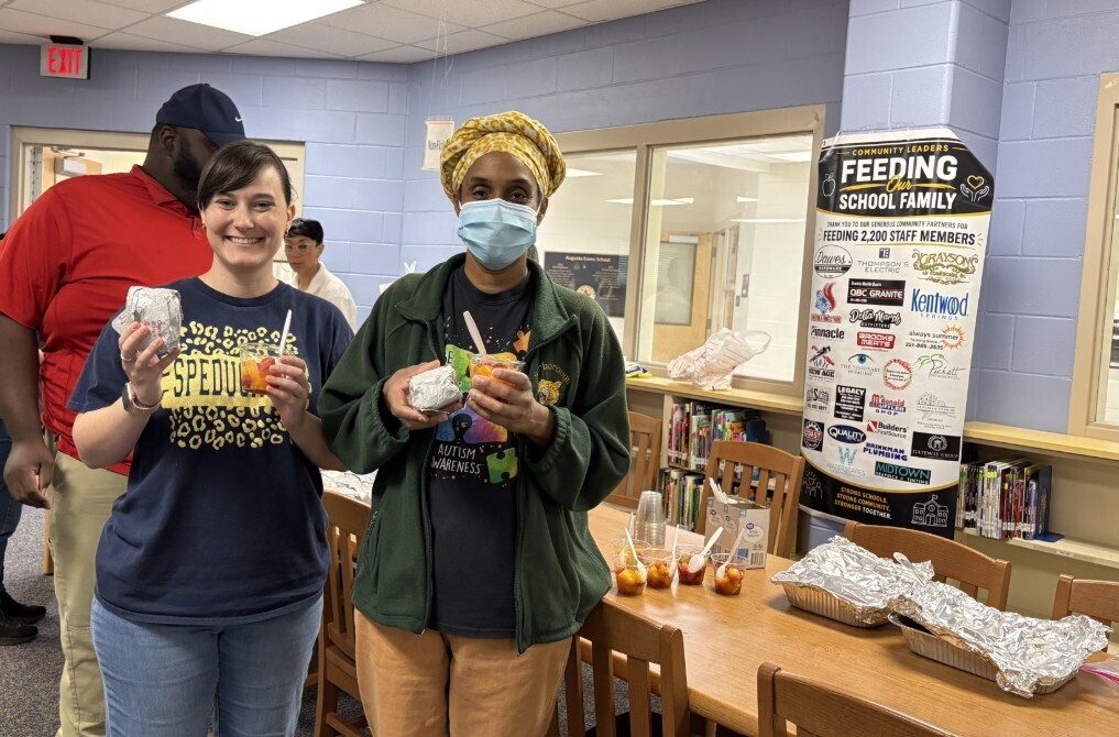 Our school counselor with a para professional smiling with their breakfast 