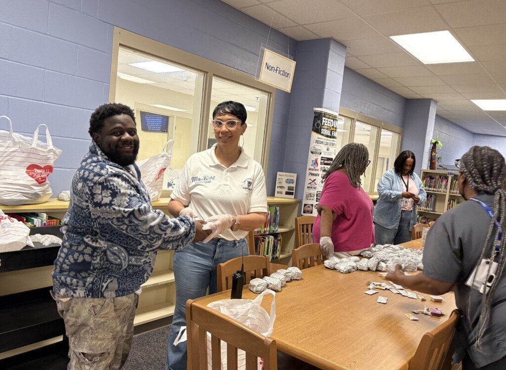 Mrs. Kidd shaking hands with a para while passing out Chick fil A to the staff. Breakfast was donated from Multiple organizations within the Mobile Bay area 