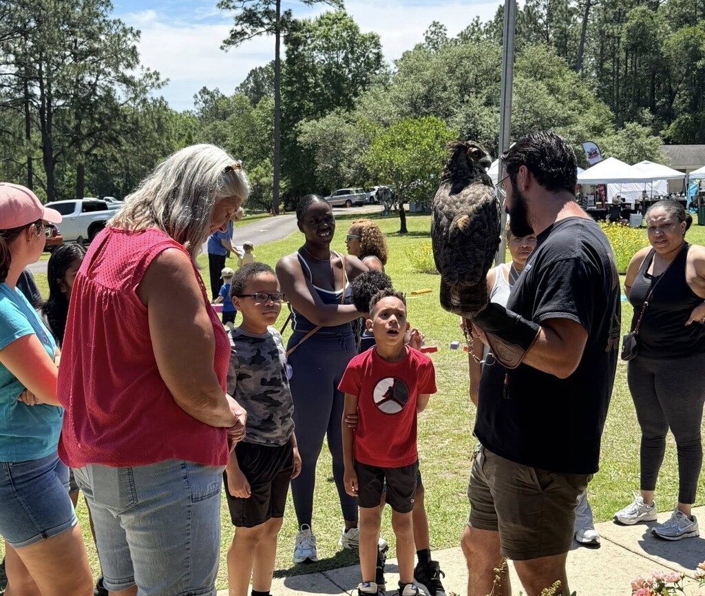 A man holds a hawk while children and adults look on