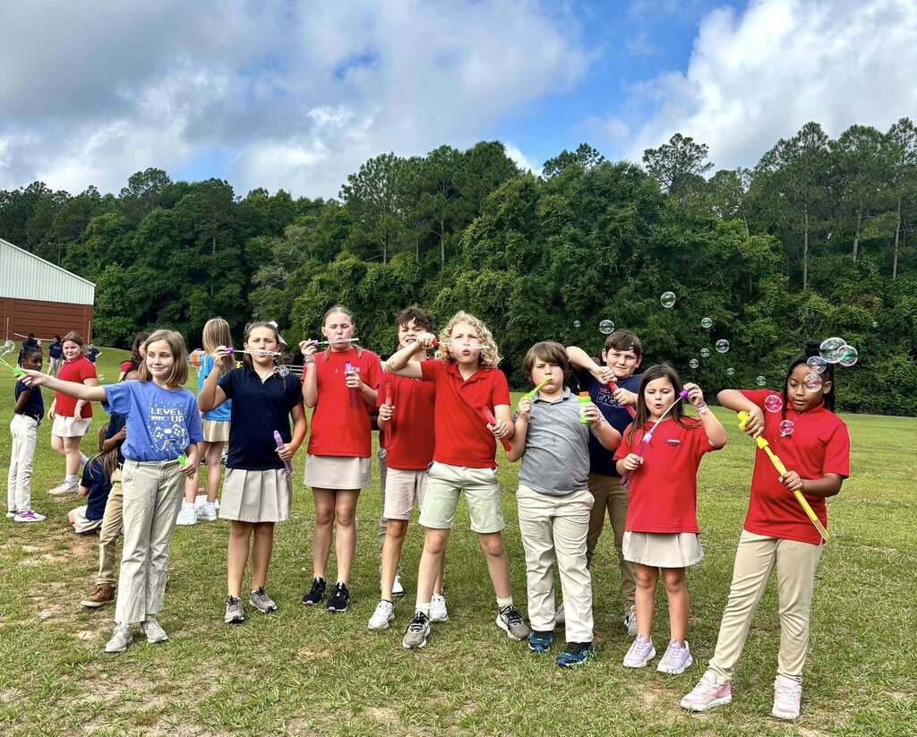 A group of students blowing bubbles in a field