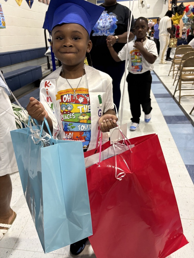 A kindergartener in a blue cap holds two gift bags