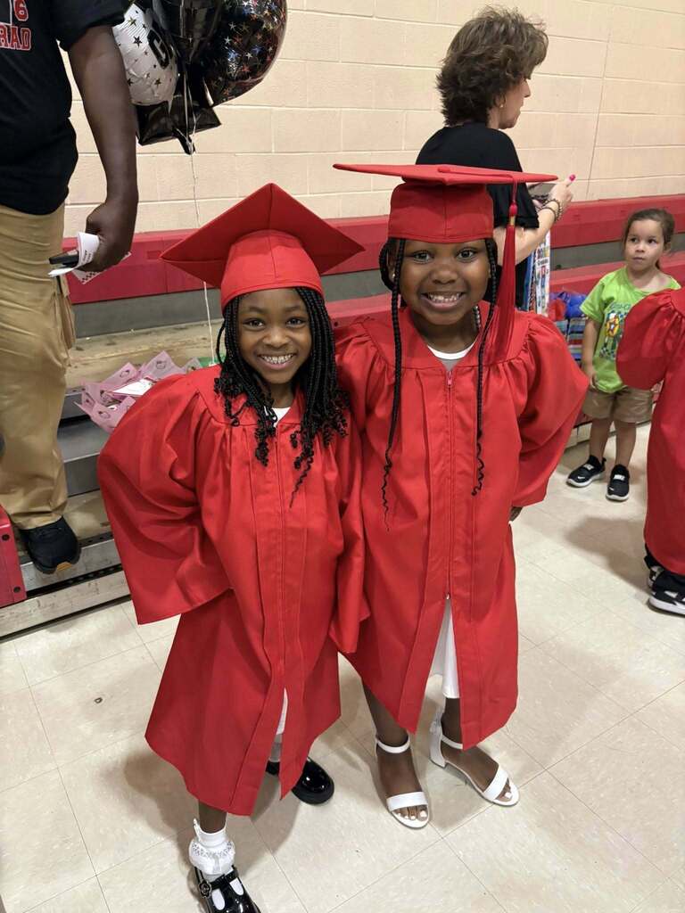 Two kindergarten students in red caps and gowns