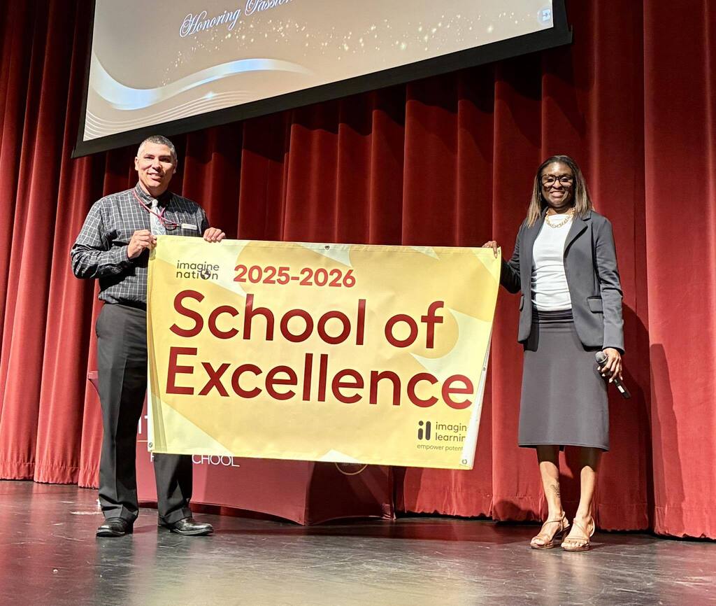 Two Citronelle High administrators holding a banner that reads "School of Excellence"